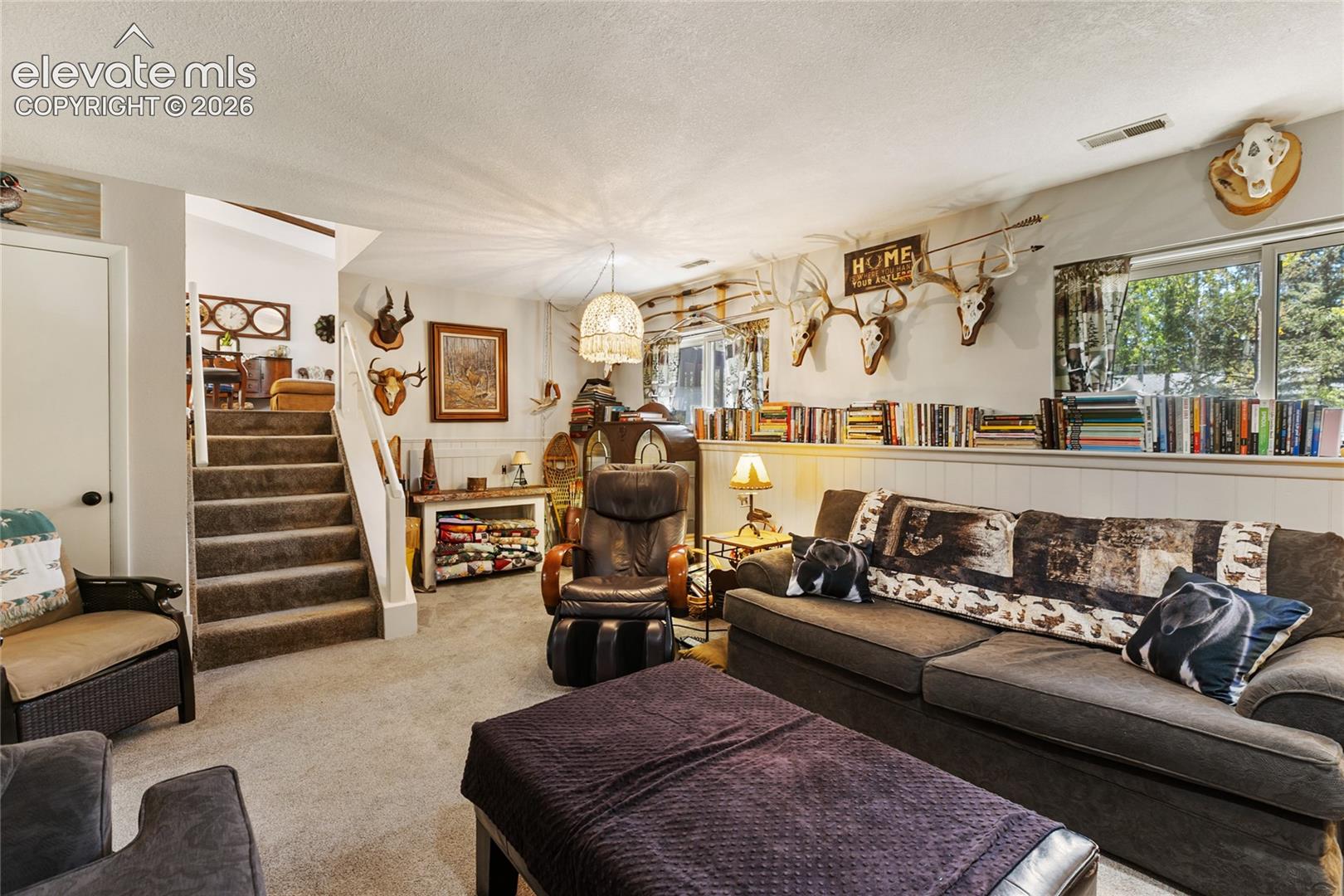 Carpeted flooring, white wainscoting, built-in shelving, white trim, and a window with exterior views