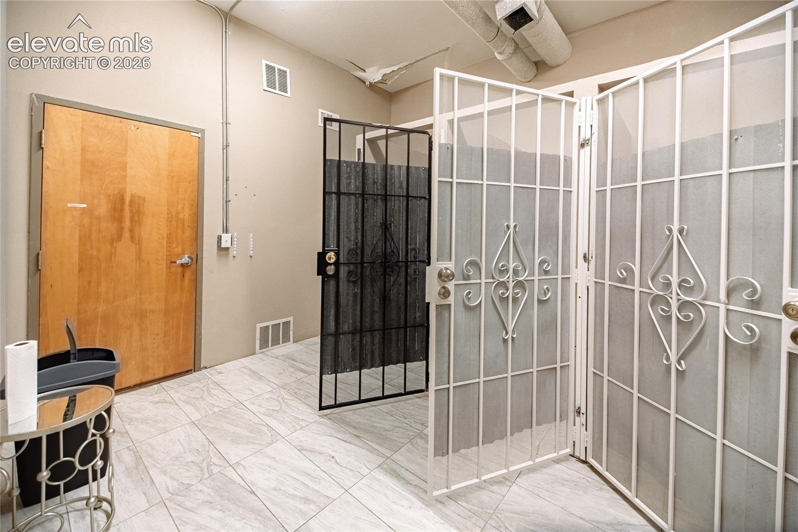 Light-toned wall paint, exposed conduit, and a wooden door create a functional interior