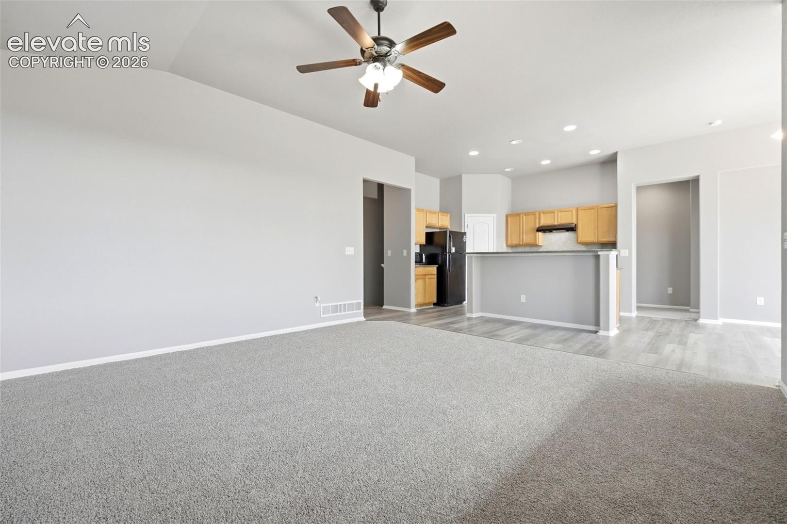 Vaulted ceiling with a ceiling fan, light wood cabinetry, black appliances, recessed lighting, and wood-finish flooring
