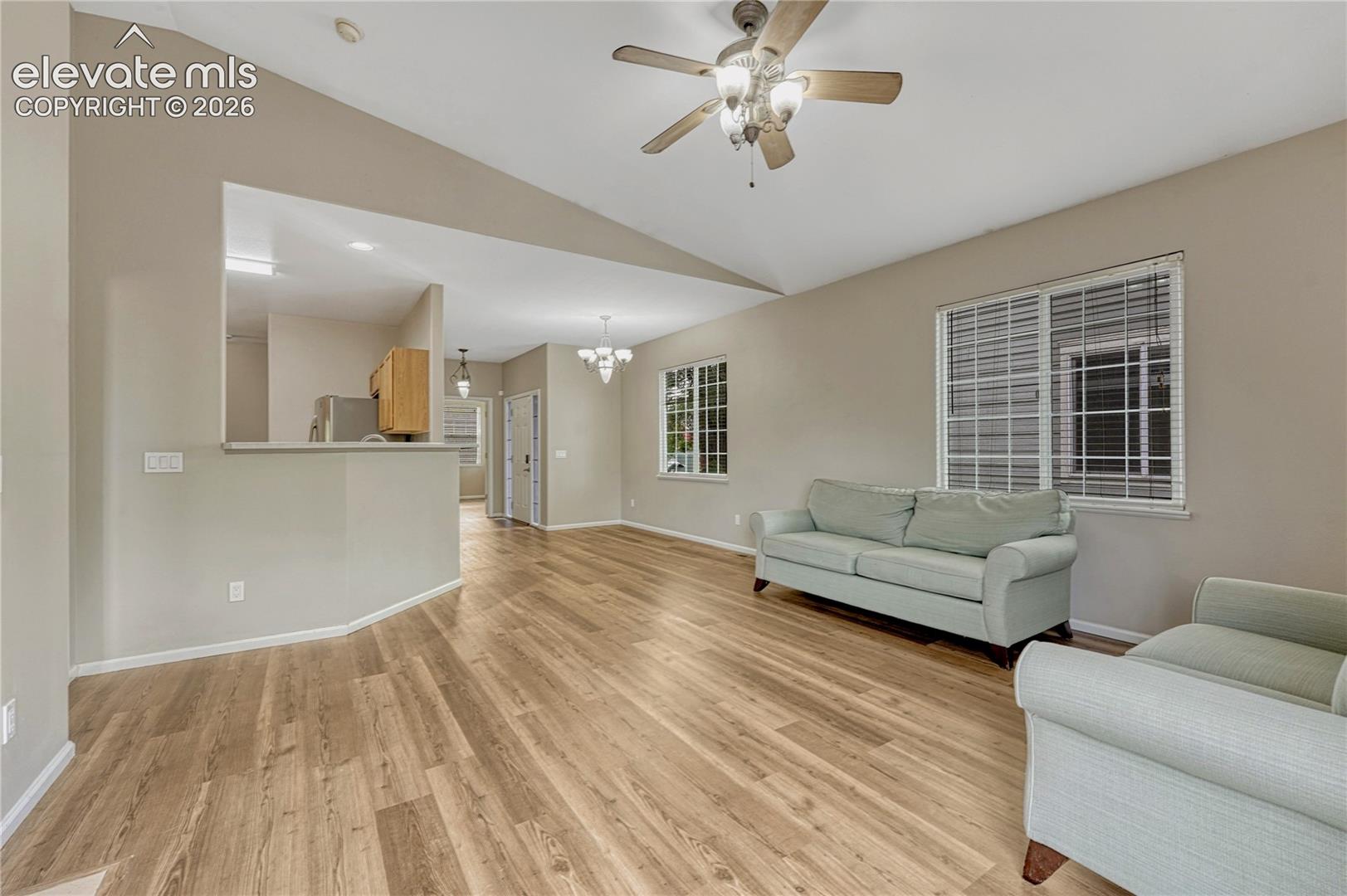 Vaulted ceilings, wood-finish flooring, multi-pane windows with integrated shutters, and dual ceiling-mounted lighting fixtures