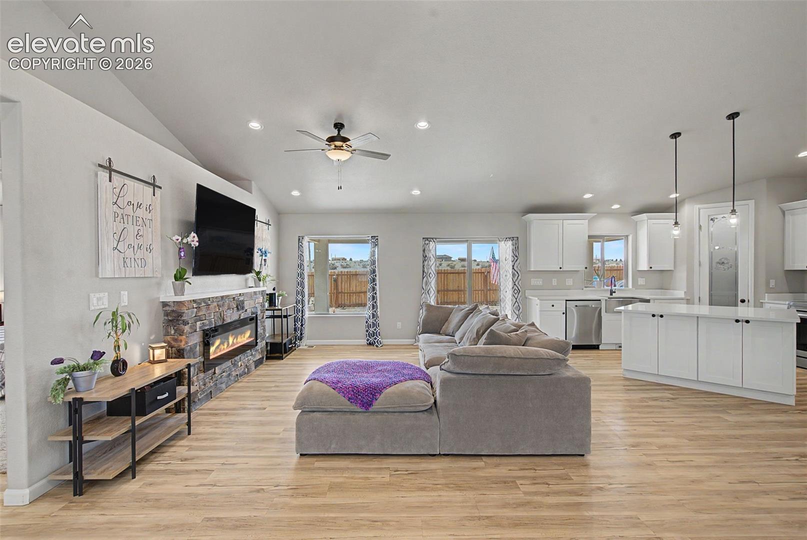 Open-concept living area with wood-finish flooring, vaulted ceilings, and recessed lighting