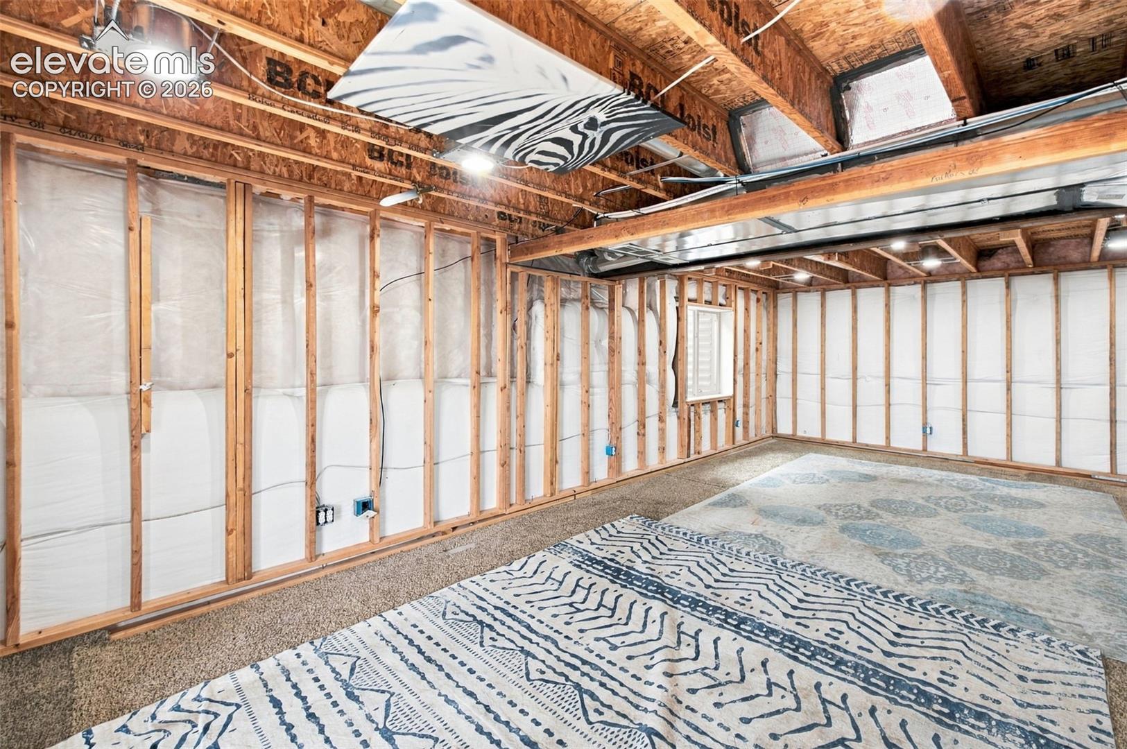 Unfinished basement area featuring exposed wood-joist ceiling, exposed wall framing, integrated recessed lighting, and vapor barrier wall insulation