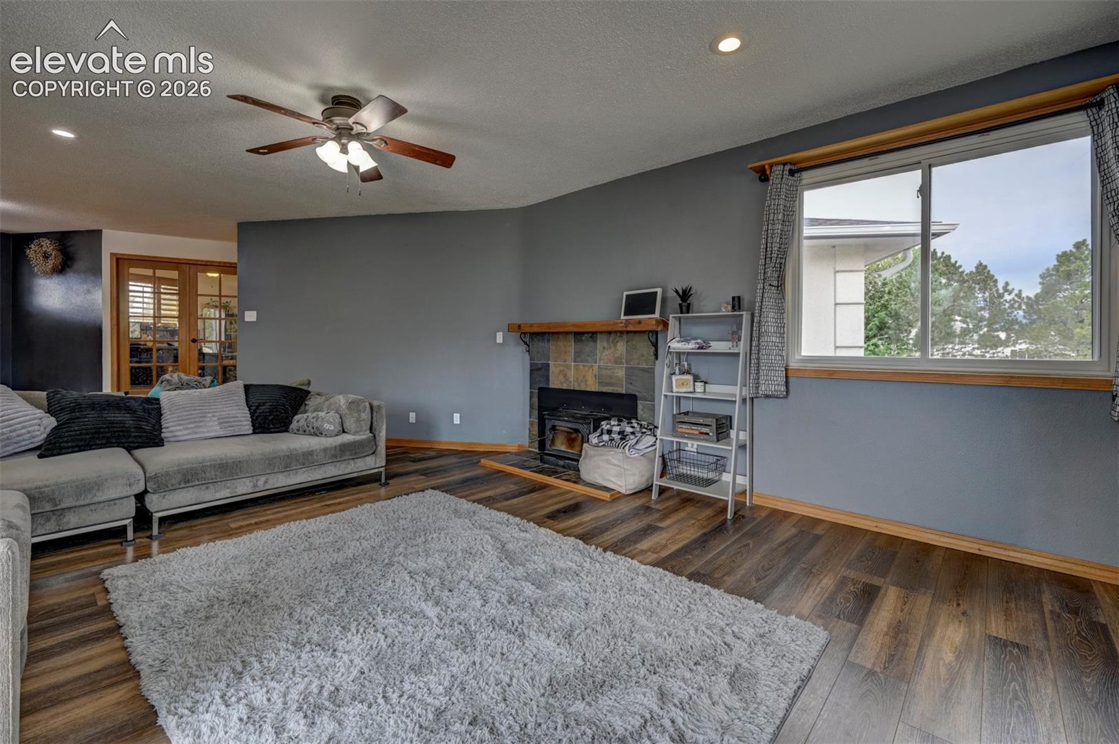 Wood-finish flooring, ceiling fan, recessed lighting, fireplace with stone surround, and wood mantle