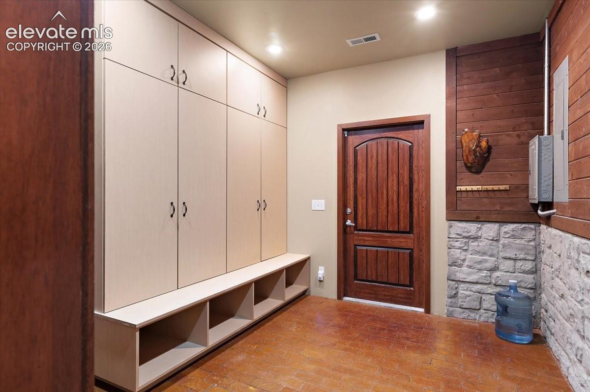 Spacious 10 ft. X 11 ft. mudroom with lots of storage cabinets and seating for removing shoes. Access to the tennis coutrt and arean, utility room and one of the Generator Transfer Panel.