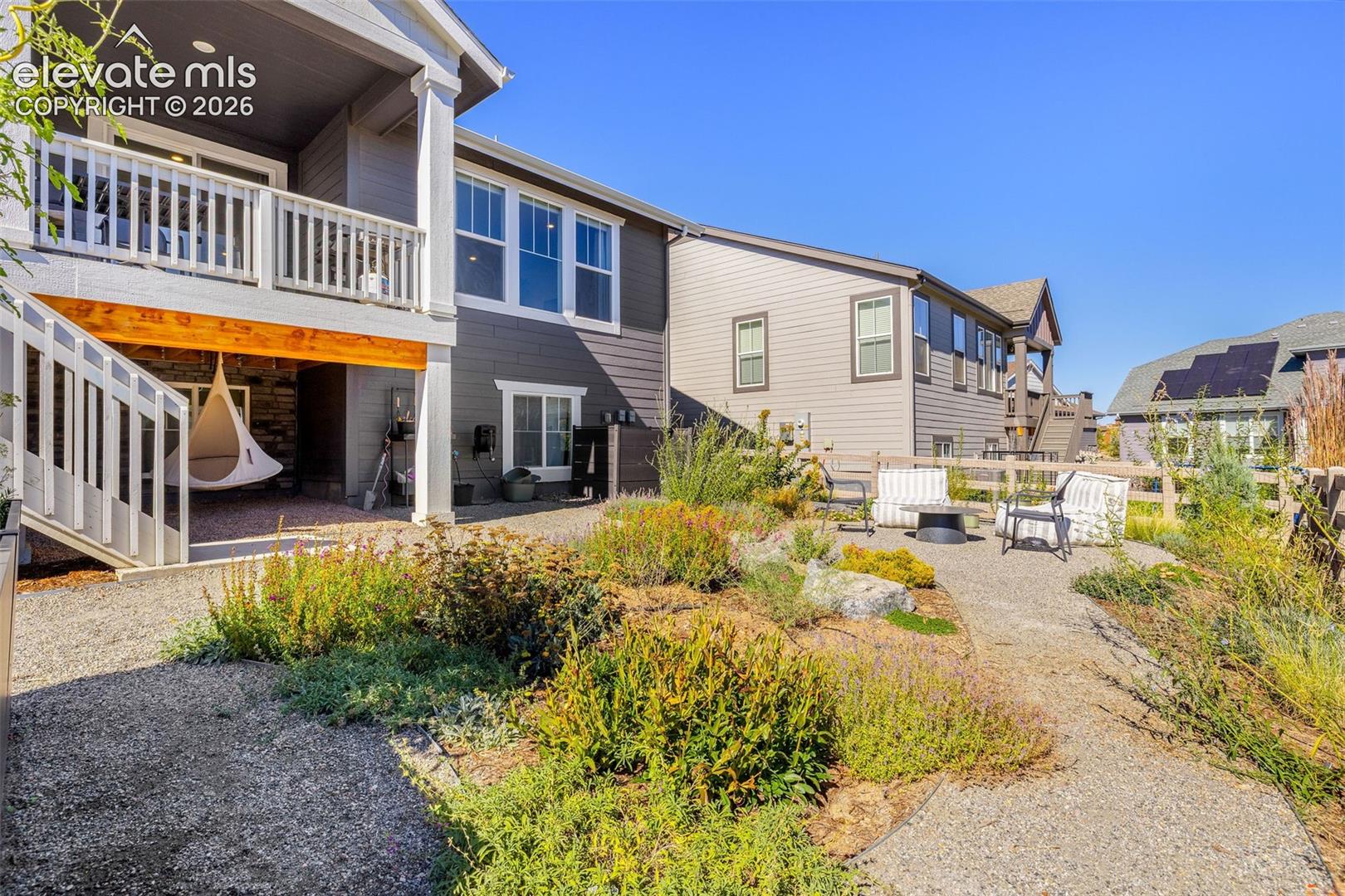 Expansive gravel patio featuring a fire pit, mature landscaping, and a fenced perimeter