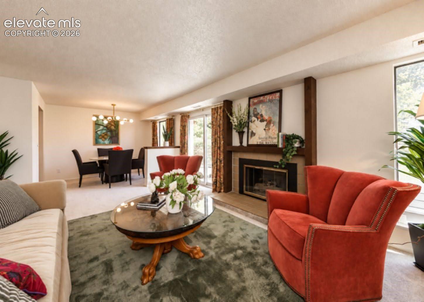Living area featuring a fireplace with a masonry surround, wood-finished mantel supports, sliding glass doors, and a multi-light chandelier