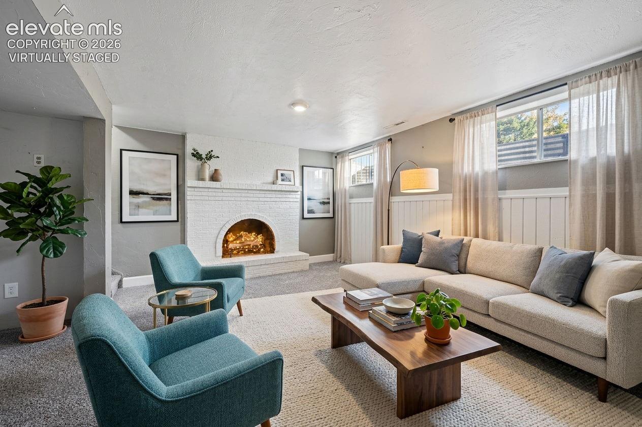 Virtually staged family room in basement with Painted brick fireplace with a rounded hearth, wainscoting wall treatment, and carpeting