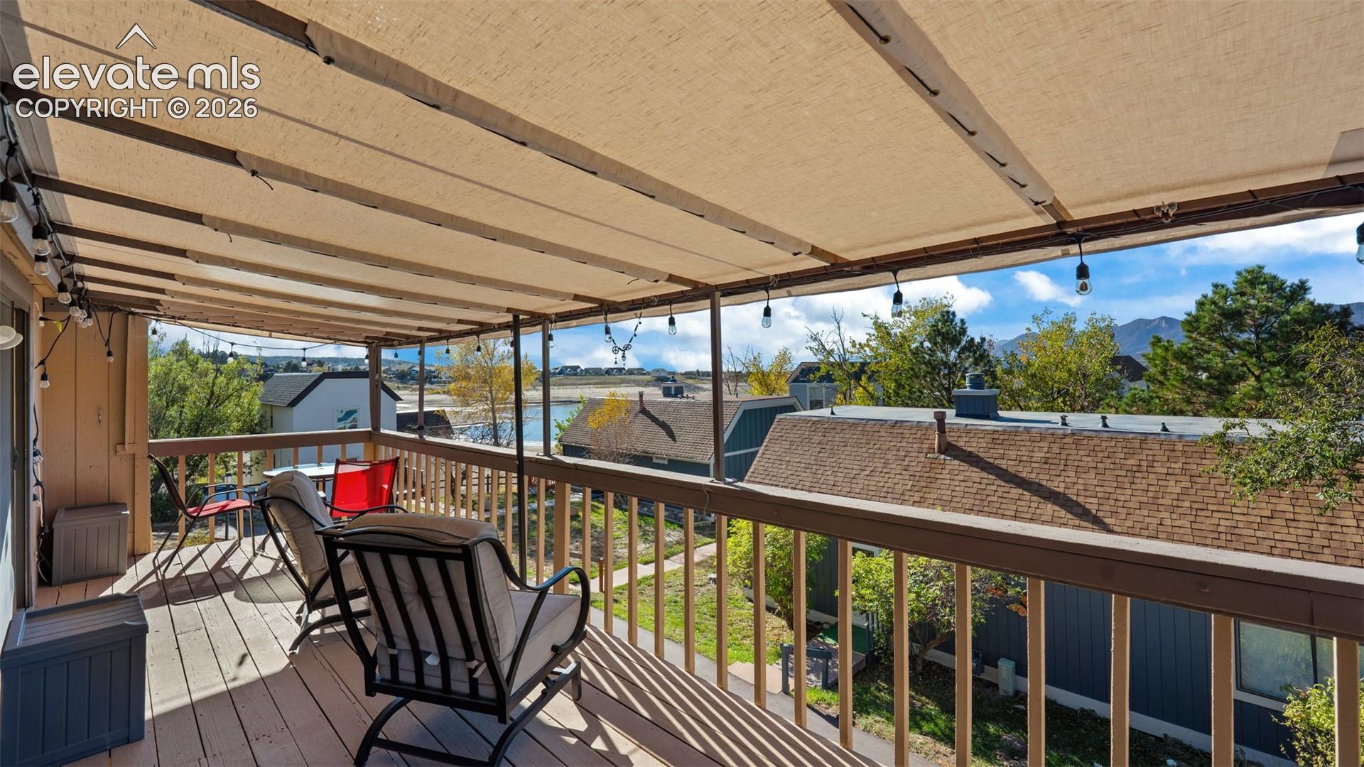 Covered deck featuring a retractable fabric canopy, wooden decking, and a wooden railing overlooking a mountain landscape