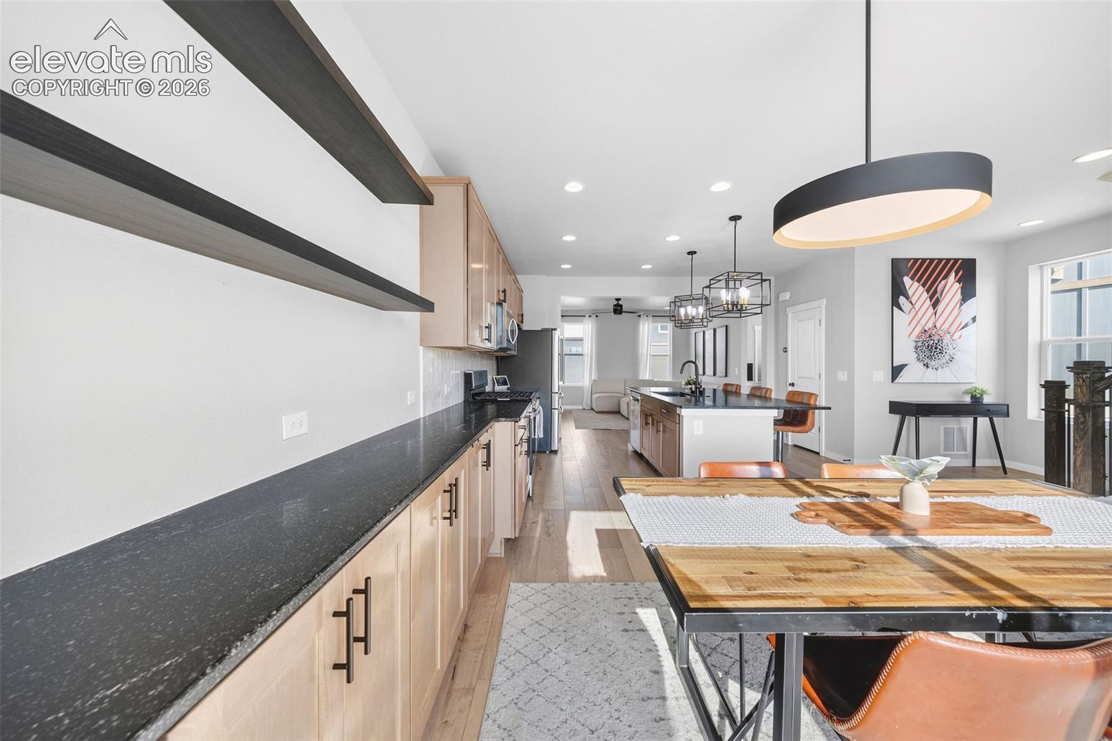 View of the dining area, kitchen and living room from the balcony entrance. The floor plan is bright and open. 