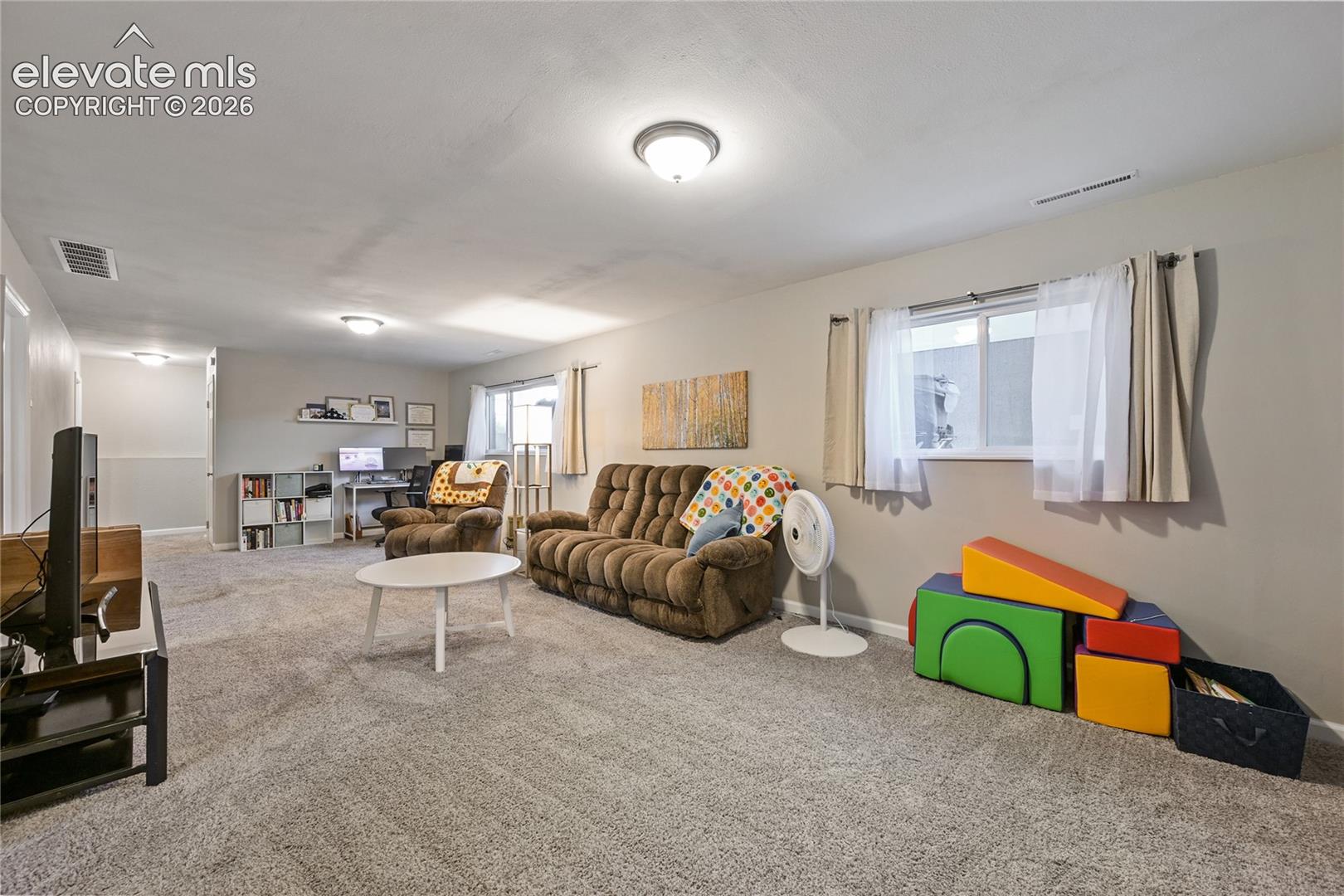 Neutral-toned interior featuring wall-to-wall carpeting, multiple flush-mount ceiling light fixtures, and windows with white casings