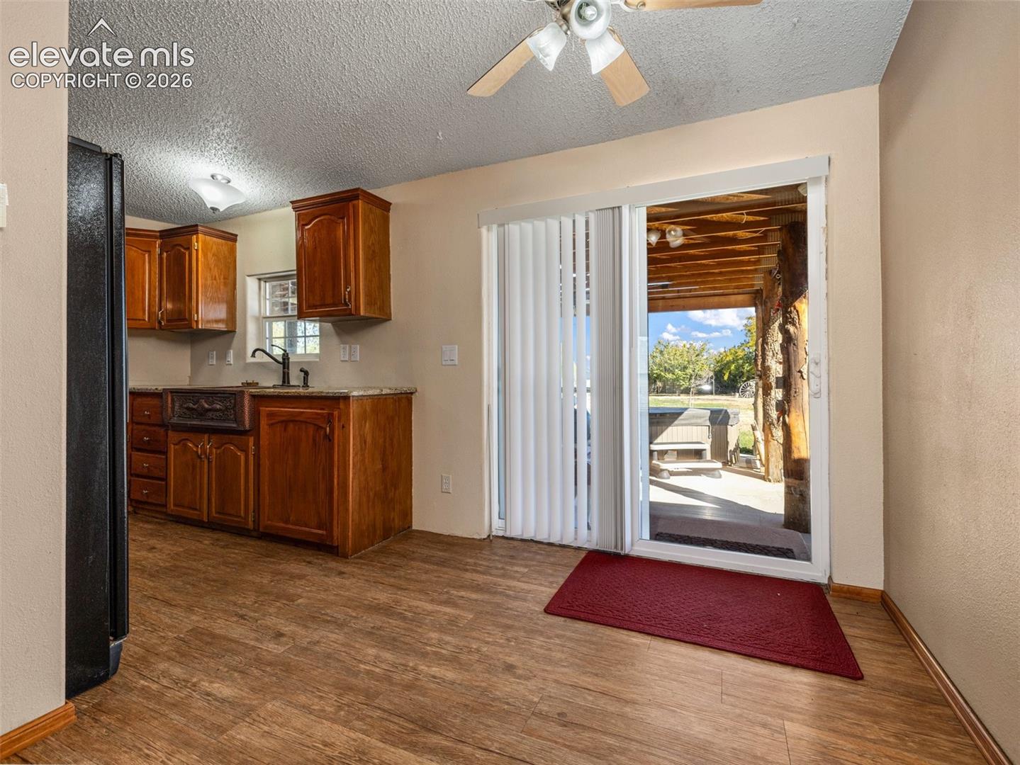 Kitchen featuring wood cabinetry, stone-finish countertops, wood-finish flooring, and sliding glass doors with access to a covered patio