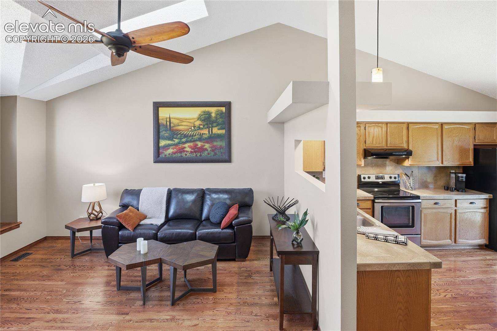 VAULTED CEILINGS, WOOD-FINISH FLOORING, CEILING FAN, AND BUILT-IN CABINETRY FEATURING A PENINSULA AND OVERHEAD LIGHTING