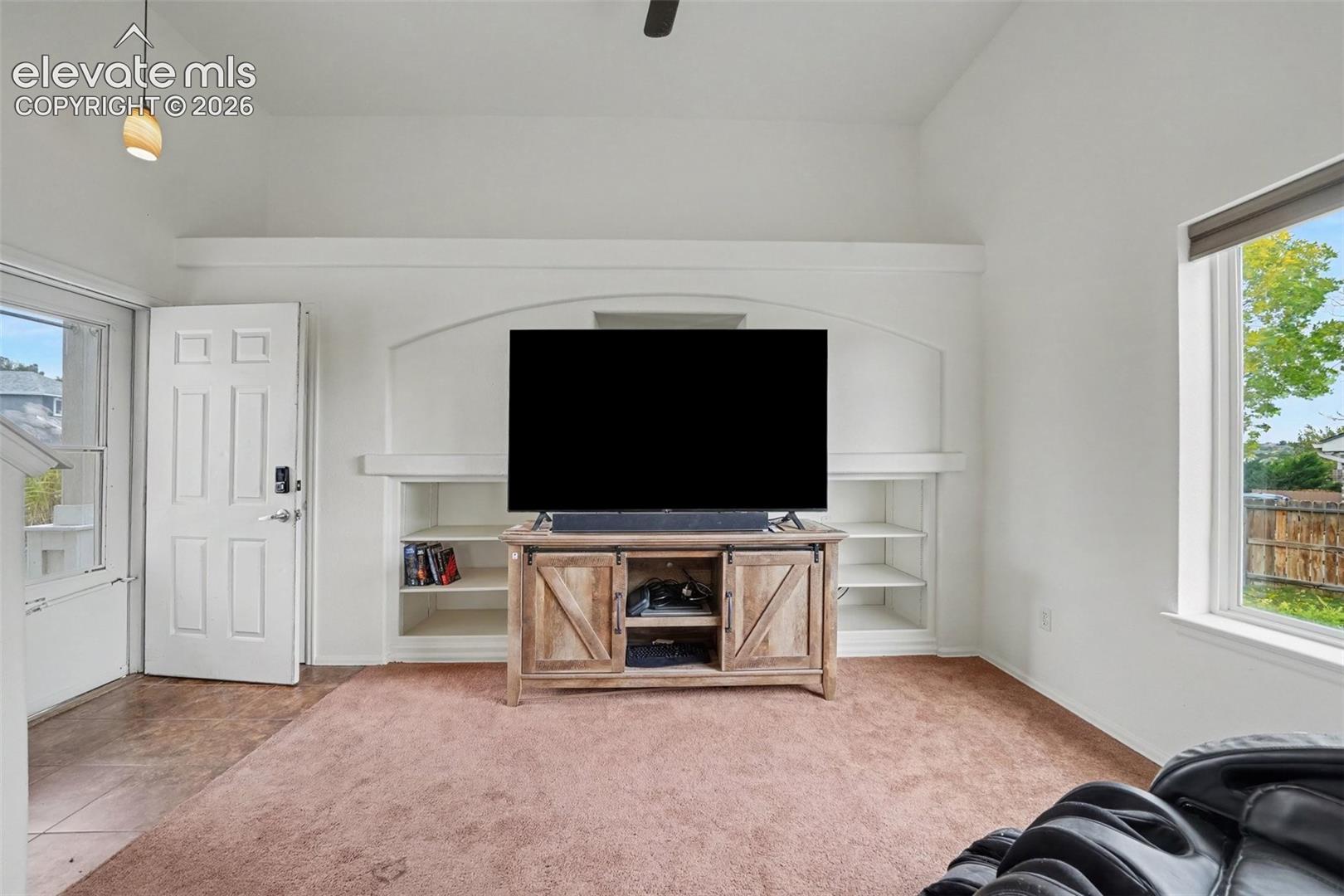 Vaulted ceilings, custom built-in shelving with arched architectural detailing, and large windows providing natural light