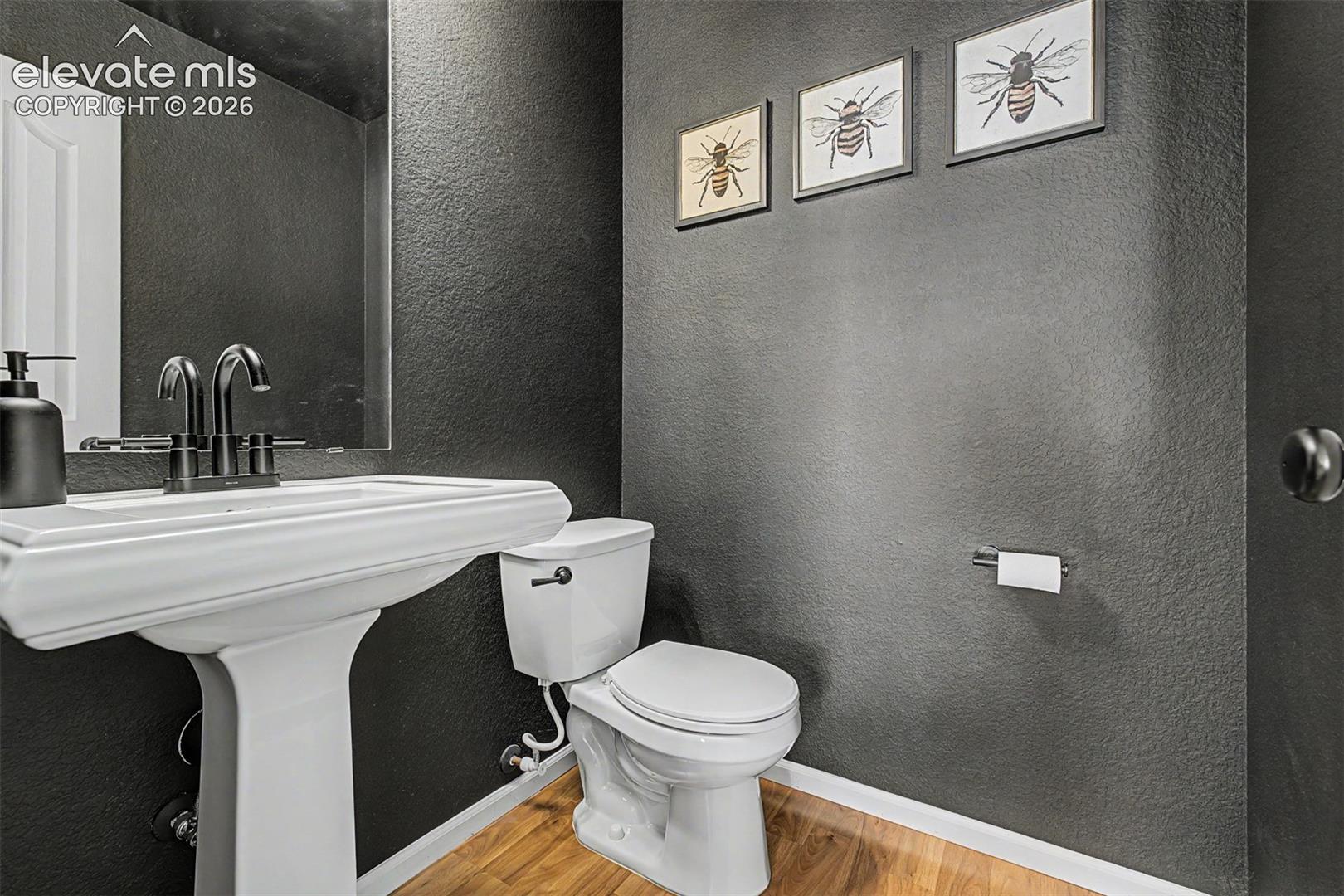 A bold charcoal accent wall, sleek white pedestal sink, and matte-black fixtures give this powder room a dramatic, design-forward personality that makes a lasting impression on guests.