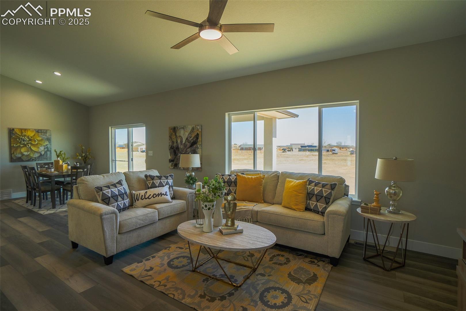 Living room featuring vaulted ceiling, LTV / wood-style floors, ceiling fan, and a wealth of natural light
