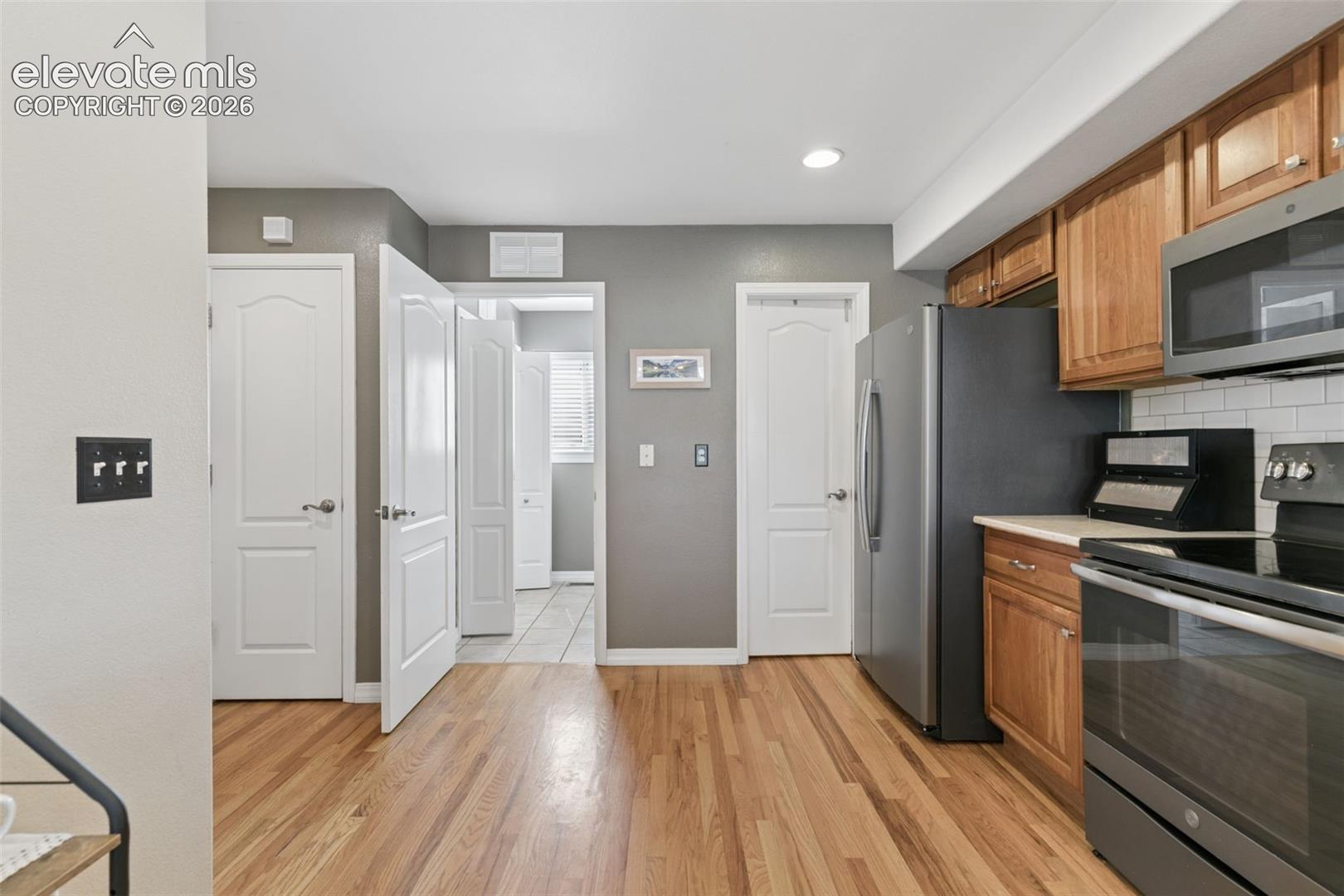 Wood-finish flooring, recessed lighting, and white subway tile backsplash