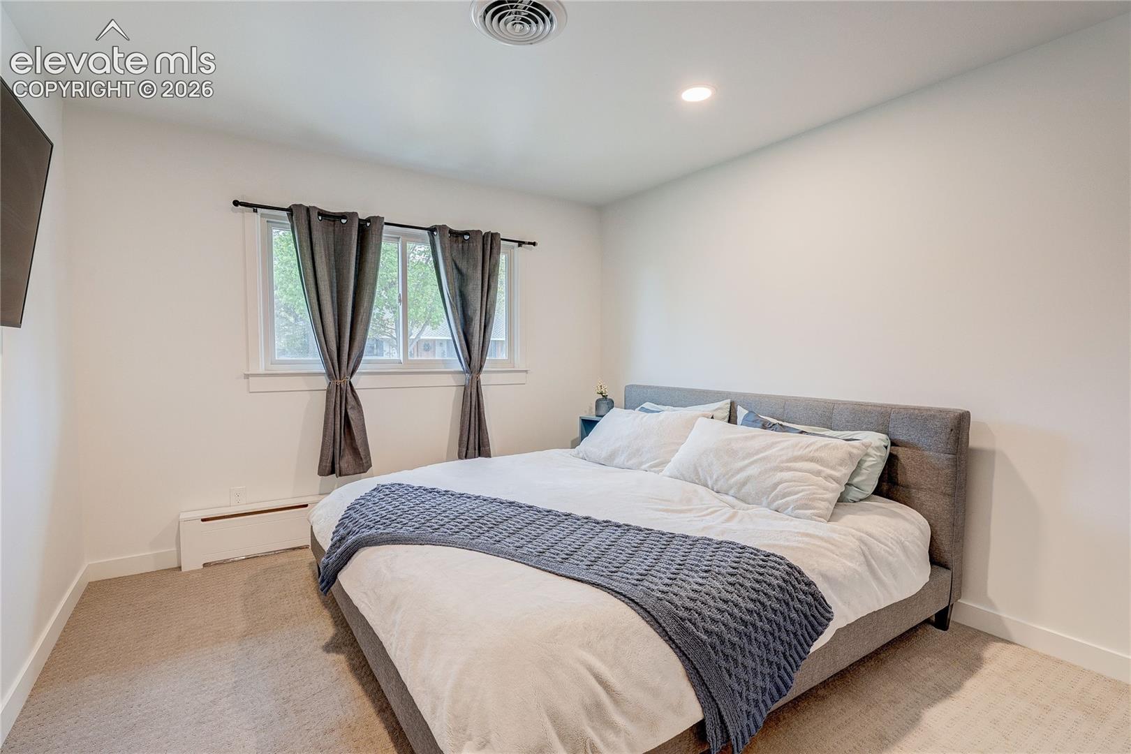 Recessed ceiling lighting, white wall finishes, window with white trim, and carpeted flooring
