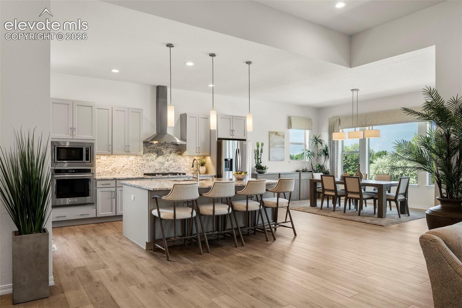 Kitchen featuring light custom cabinetry, stainless steel appliances, granite countertops, and a center island with pendant lighting
