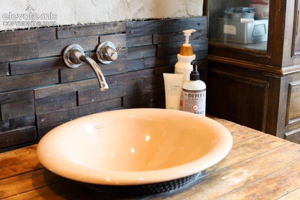 Vessel sink and wall-mounted faucet with a wood-finish countertop and dark wood-paneled backsplash