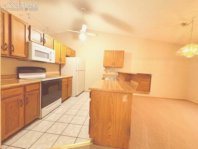 Kitchen featuring white appliances, light countertops, a peninsula, a kitchen breakfast bar, and lofted ceiling
