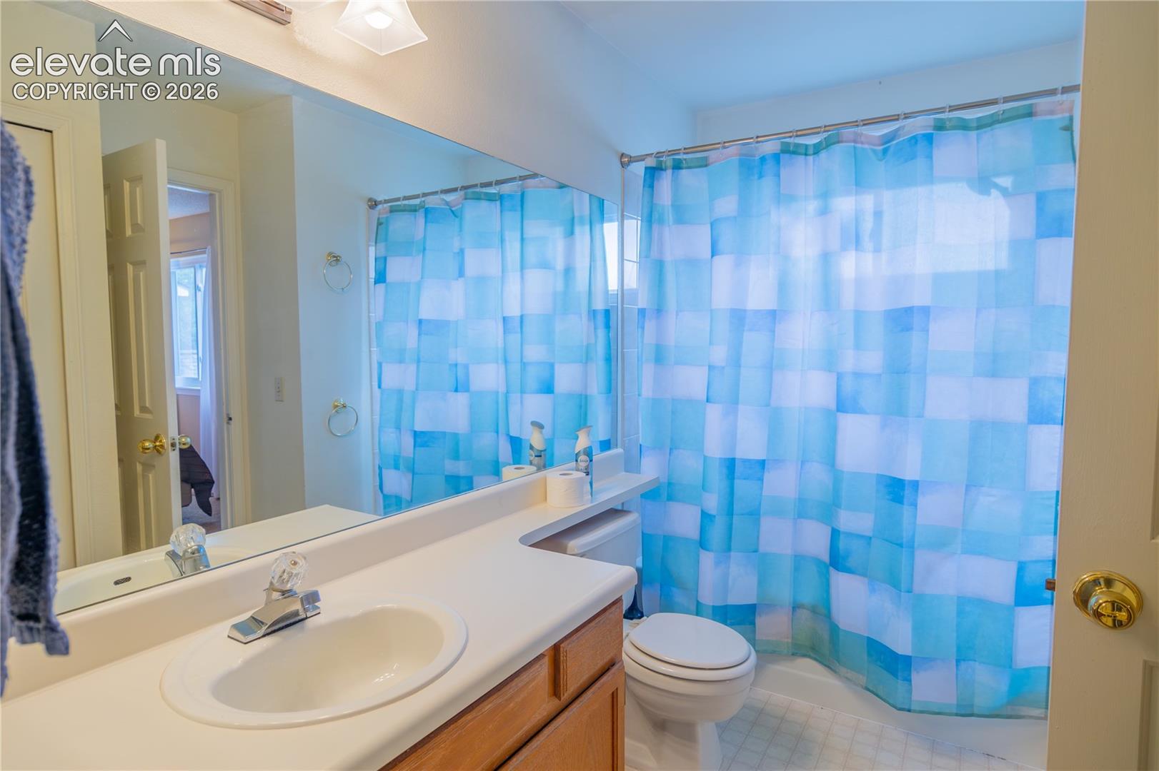 Bathroom featuring a single-sink vanity with wood-finish cabinetry, a large wall-mounted mirror, and a built-in bathtub with a shower