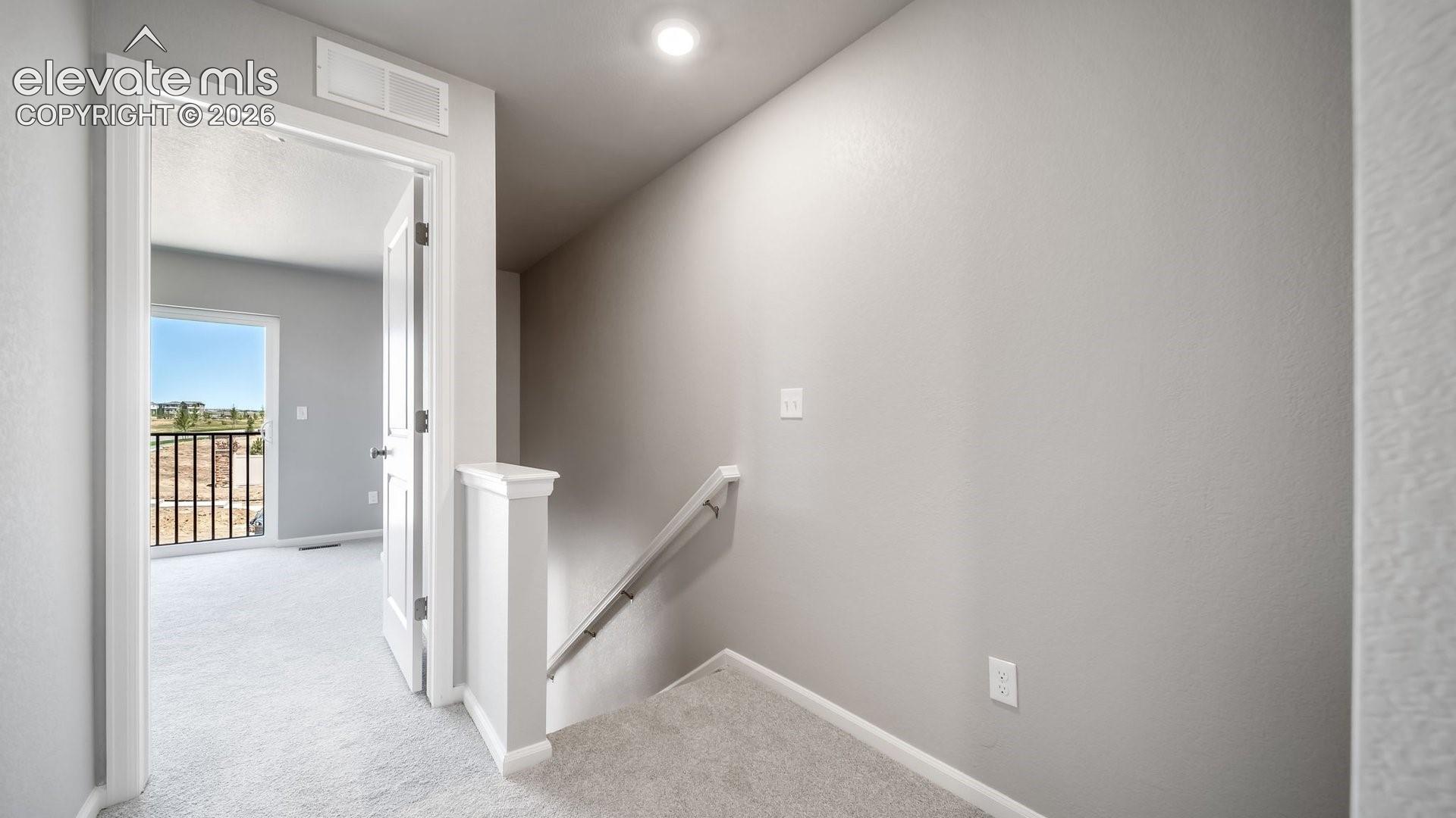 Neutral interior palette with wall-to-wall carpeting and white staircase railing featuring a decorative newel post
*photos of a model home*