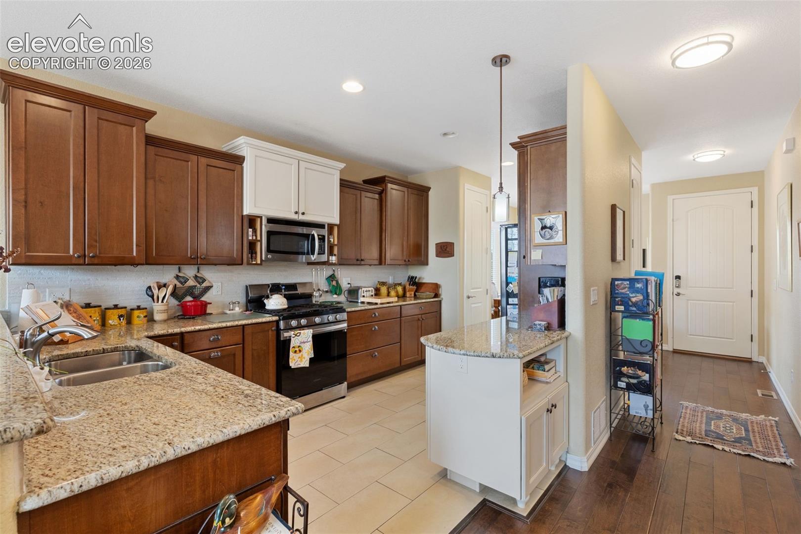 Kitchen featuring granite countertops, stainless steel appliances, and wood-finish birch cabinetry with contrasting upper white cabinets