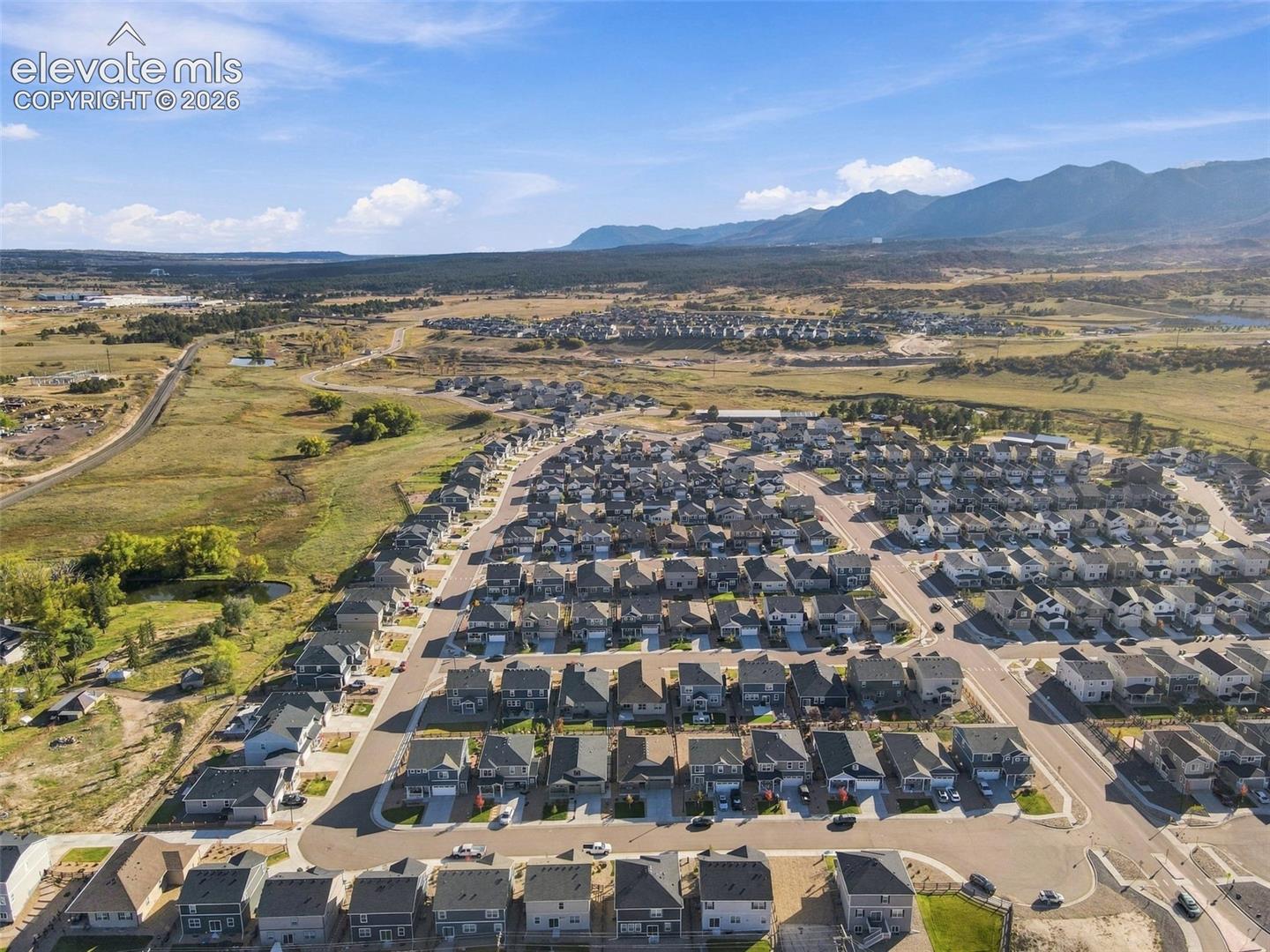Aerial perspective of a planned community featuring paved street infrastructure and a backdrop of mountain scenery