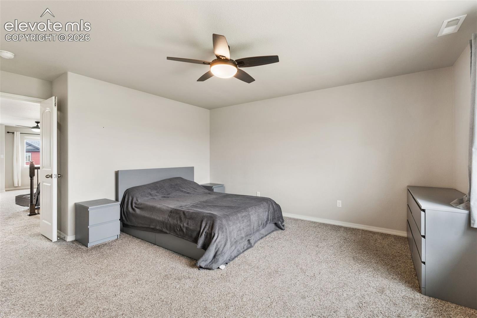 Carpeted bedroom featuring a ceiling fan with integrated lighting