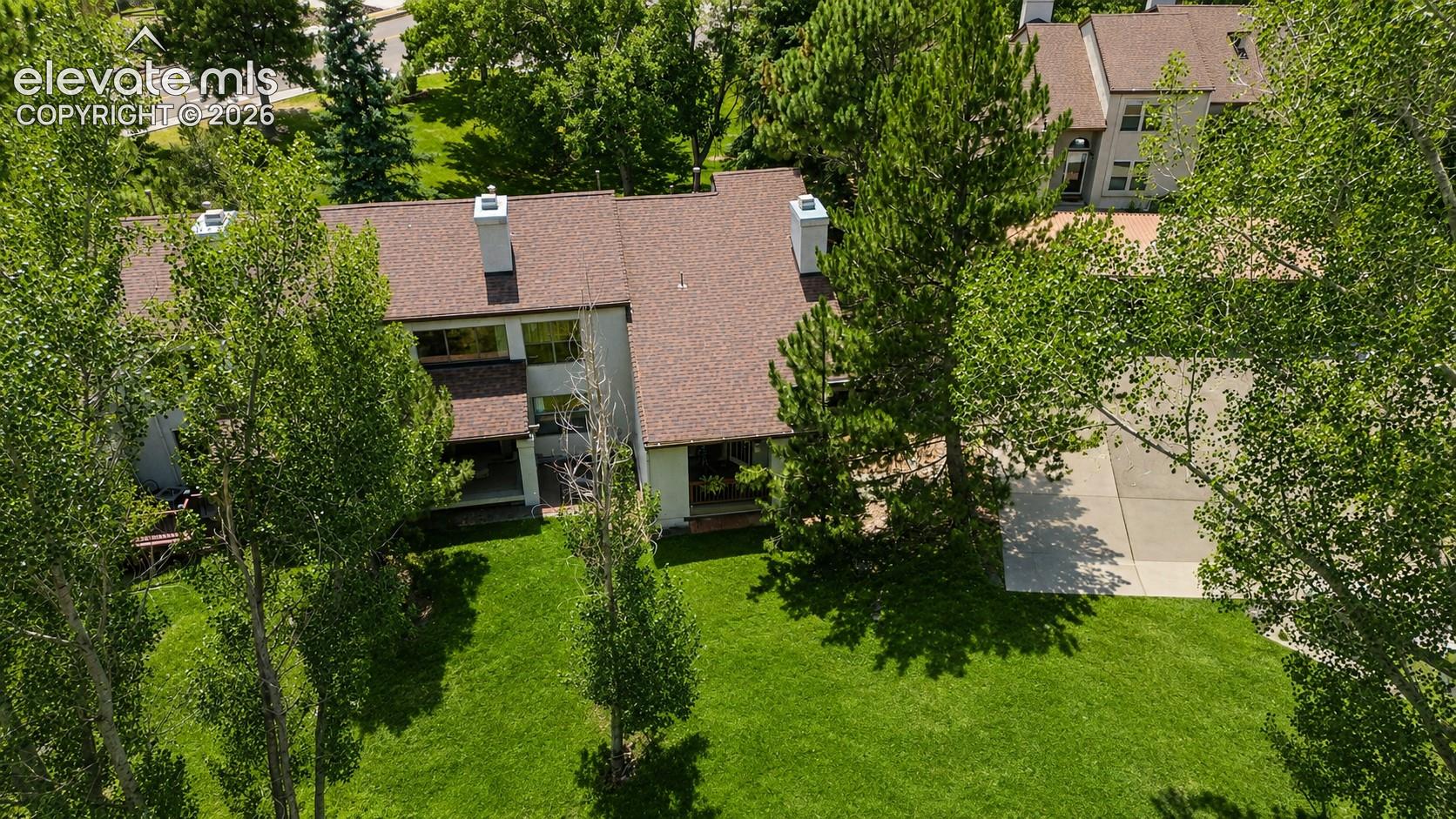 Aerial view of home, park-like grounds and parking lot with reserved covered carports.