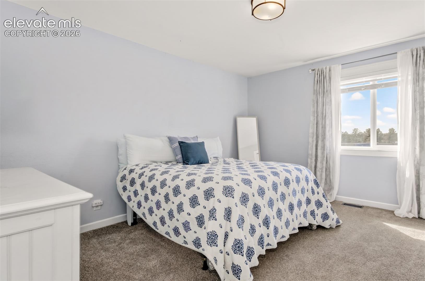 Neutral wall tones, wall-to-wall carpeting, window with natural lighting, and a flush-mount ceiling light fixture