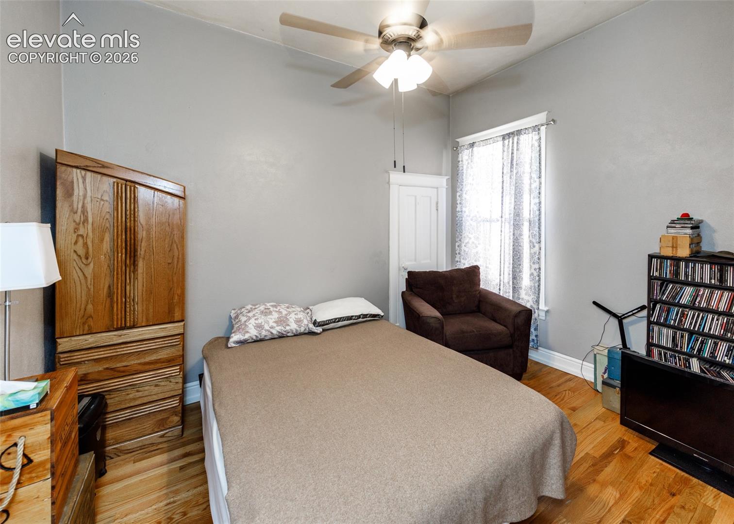 Hardwood-style flooring throughout with a ceiling fan light fixture and a window with natural light