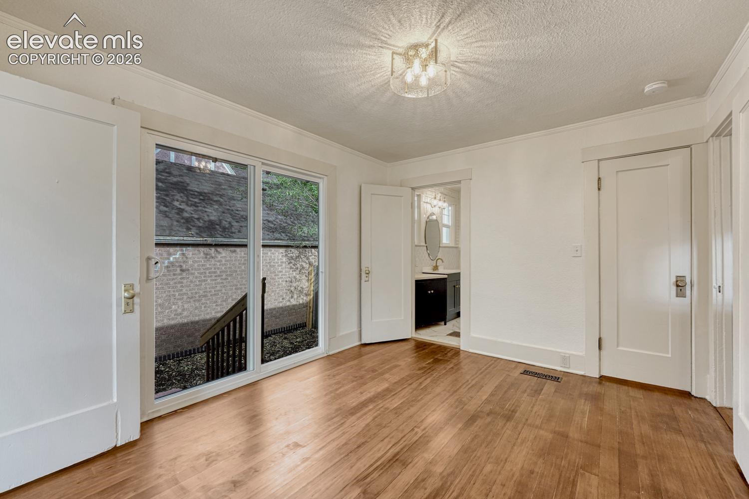 Hardwood-finish flooring, sliding glass door, white trim, recessed light fixture, and a white interior door