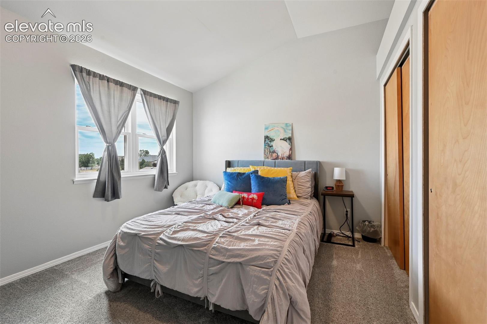 Bedroom featuring light gray walls and a vaulted ceiling