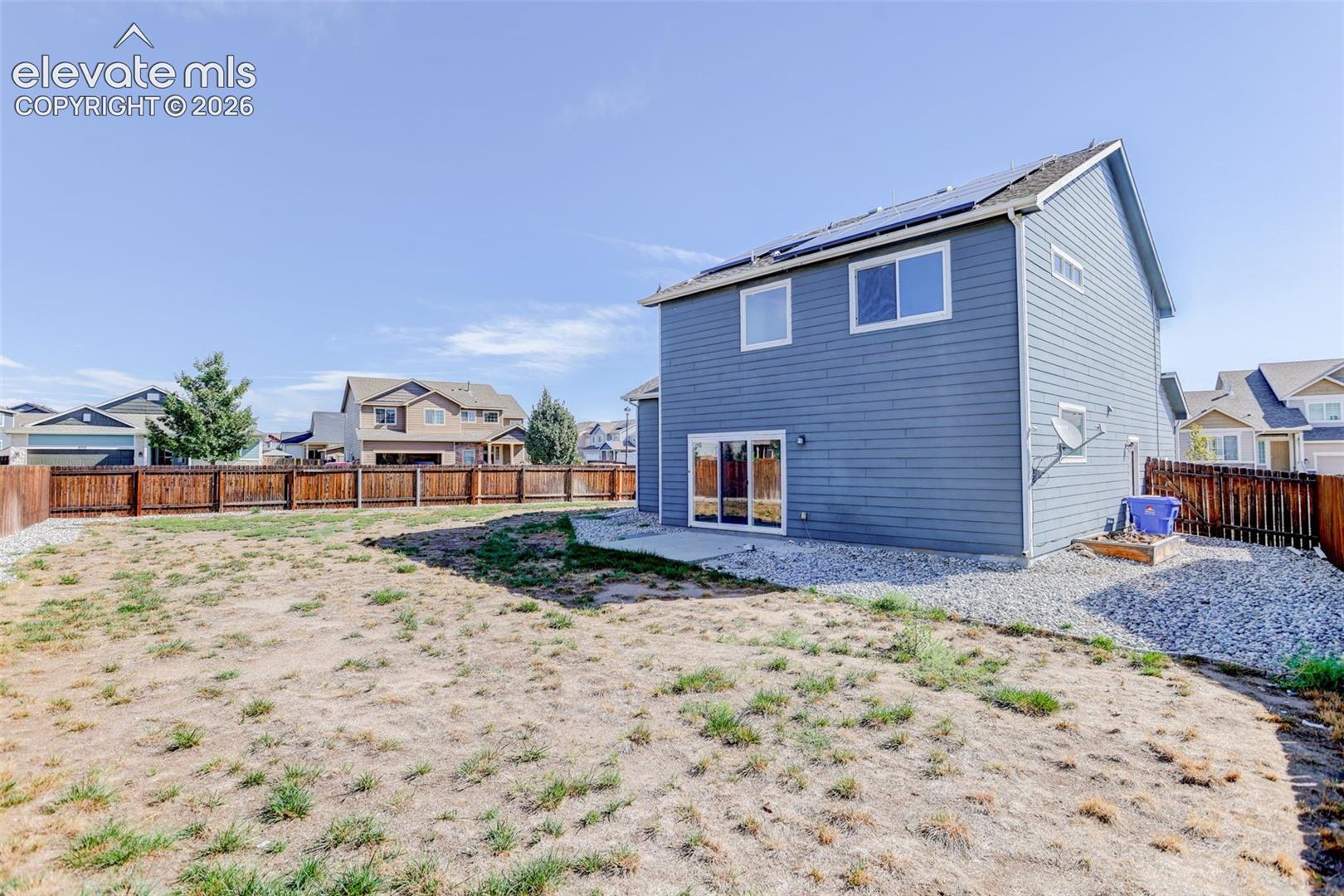 Expansive backyard with a full perimeter wood fence, a gravel border, and a concrete patio