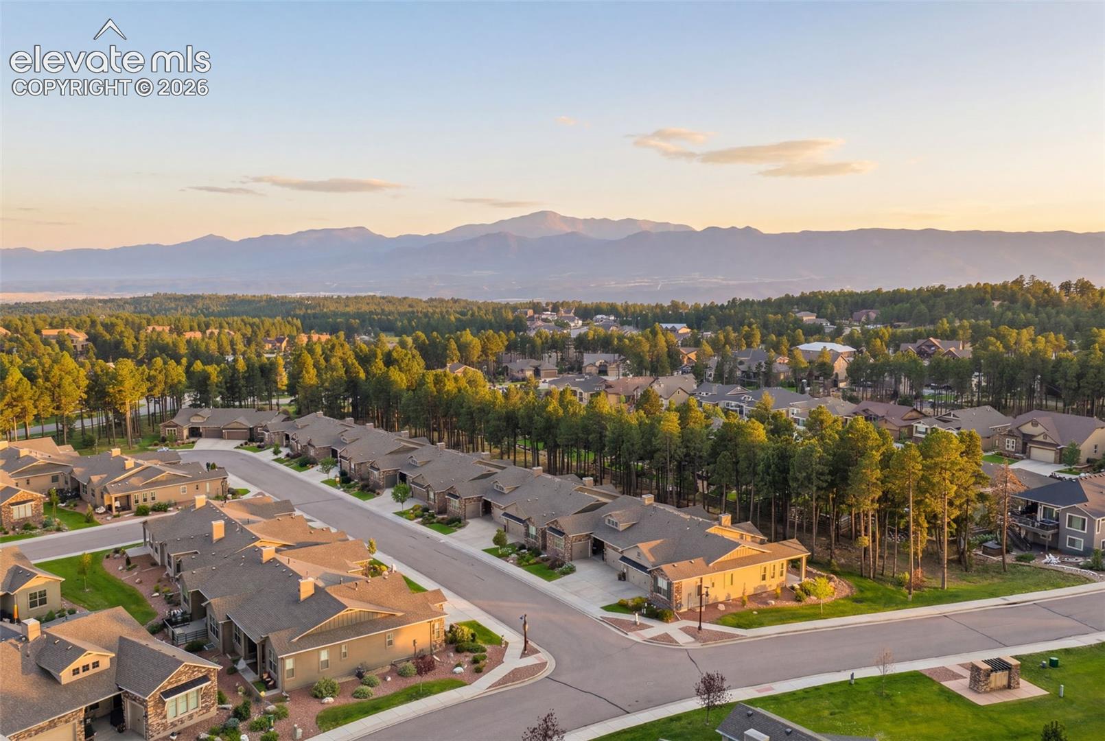 Aerial showcasing a residential community with abundant mature trees and mountainous terrain.