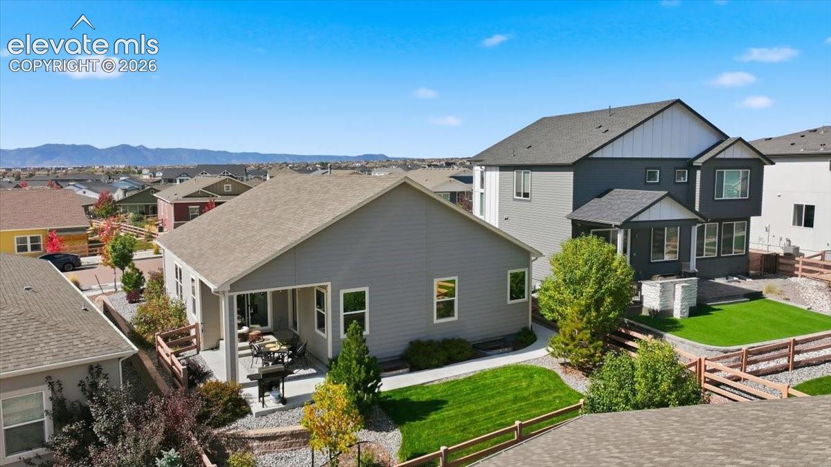 Expansive backyard featuring a covered patio, manicured lawn, and raised garden beds