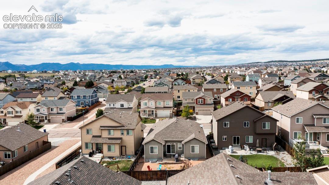 Aerial perspective of residential properties featuring shingle-style roofing, paved streets, and a distant mountain backdrop