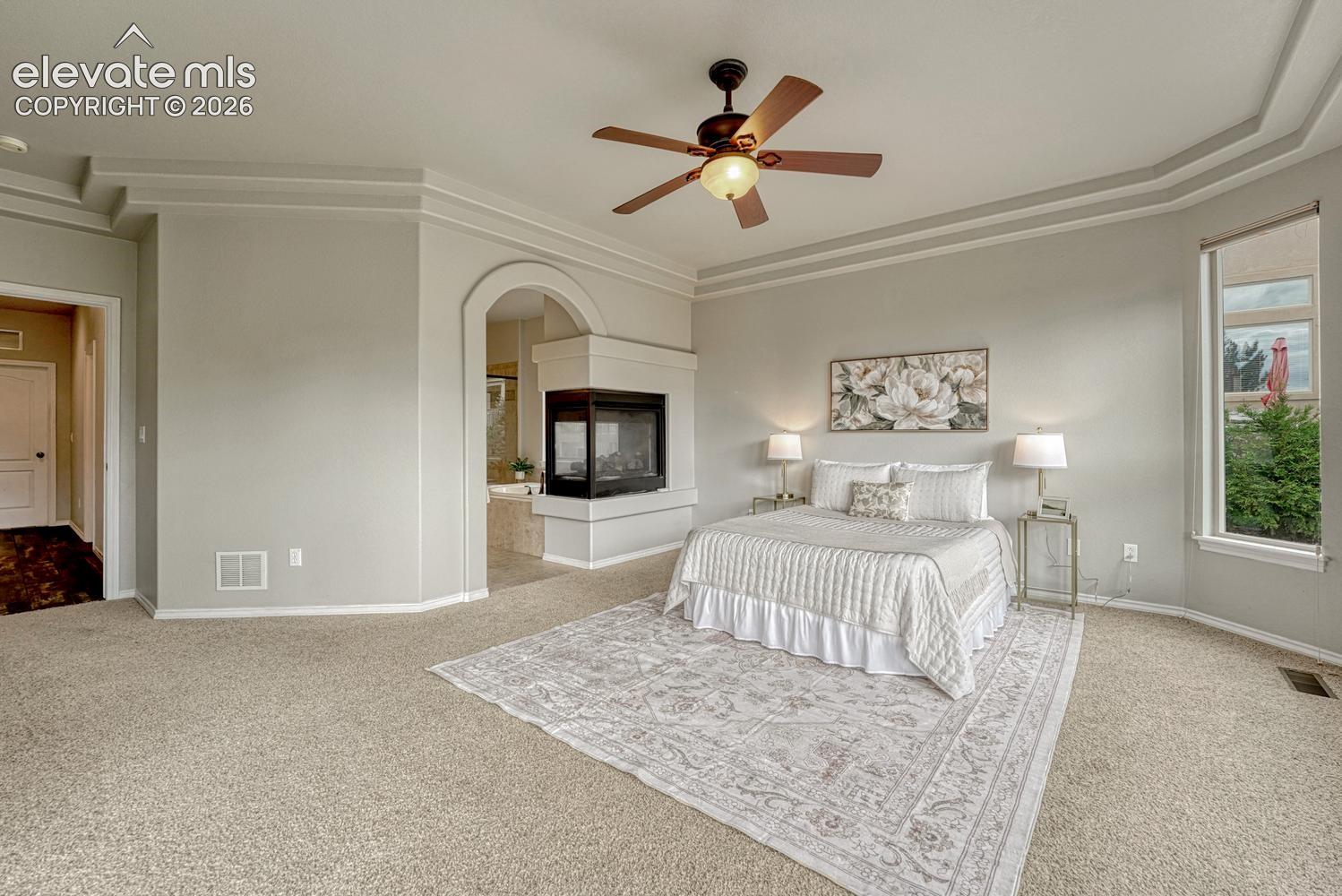 Relax in your private main level Primary Retreat with neutral carpet, a tray ceiling, lighted ceiling fan, 3-side fireplace, and adjoining 5-piece bathroom with walk in closet.