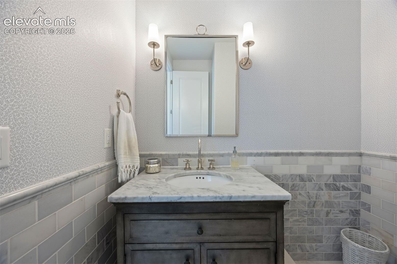 Bathroom vanity featuring a light-toned countertop, under-mount sink, and dual sconce lighting