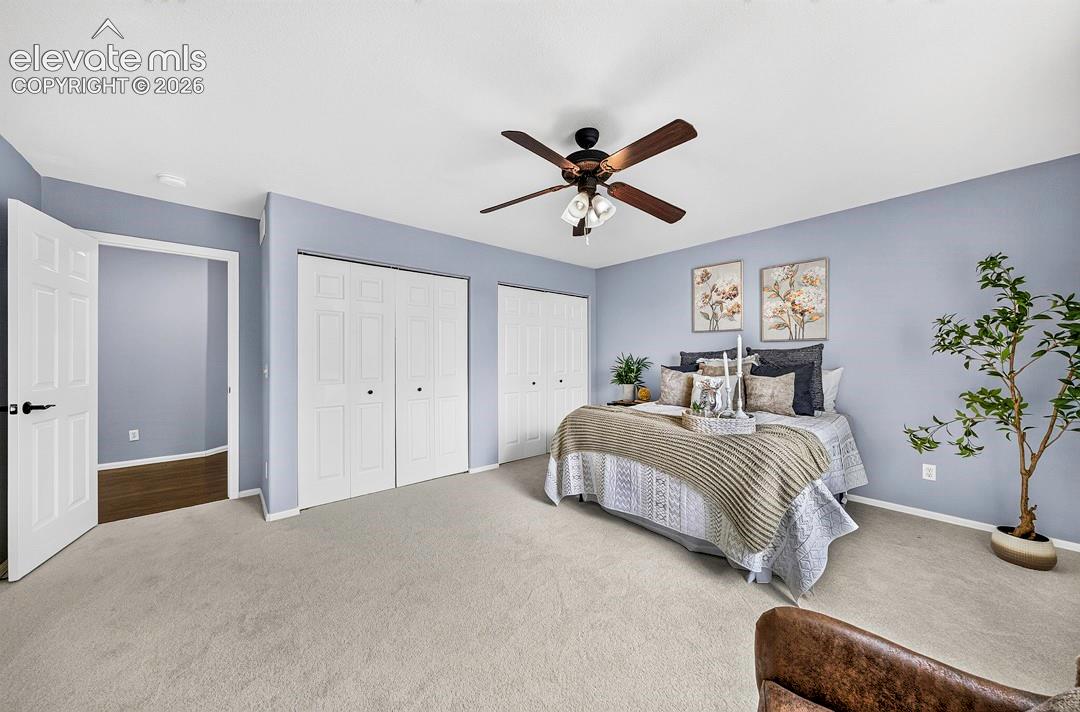 Spacious room featuring carpeting, two double-panel sliding closets, and a centrally mounted ceiling fan with integrated lighting
