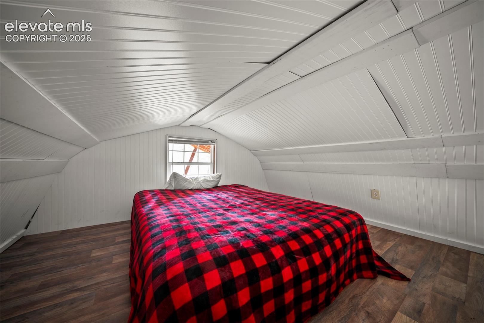 Attic space featuring white beadboard walls and ceiling, wood-finish flooring, and a single-pane window