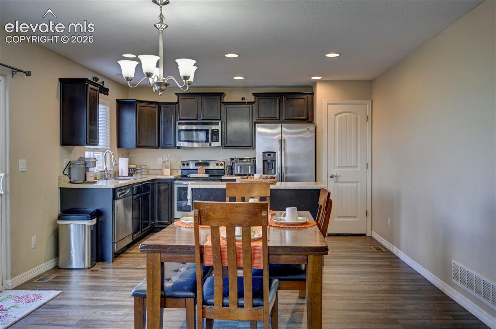 Kitchen featuring wood-finish flooring, dark cabinetry, stainless steel appliances, and recessed lighting