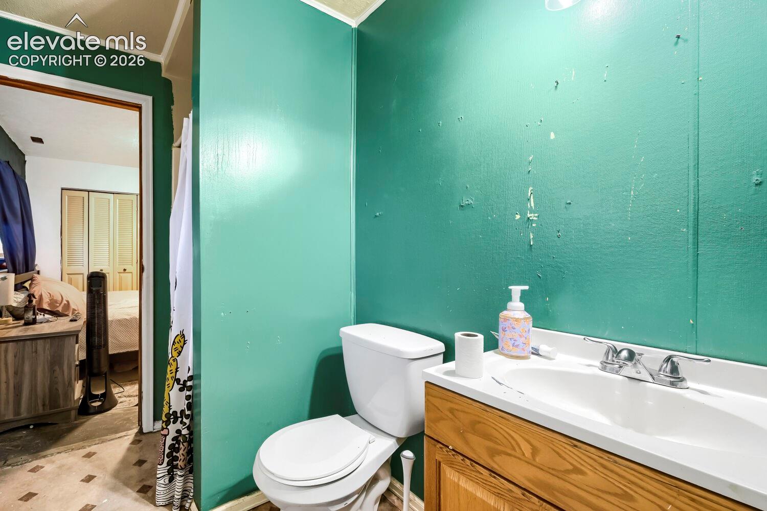 Bathroom featuring a white toilet, wood-finish vanity with an integrated sink, and chrome faucet
