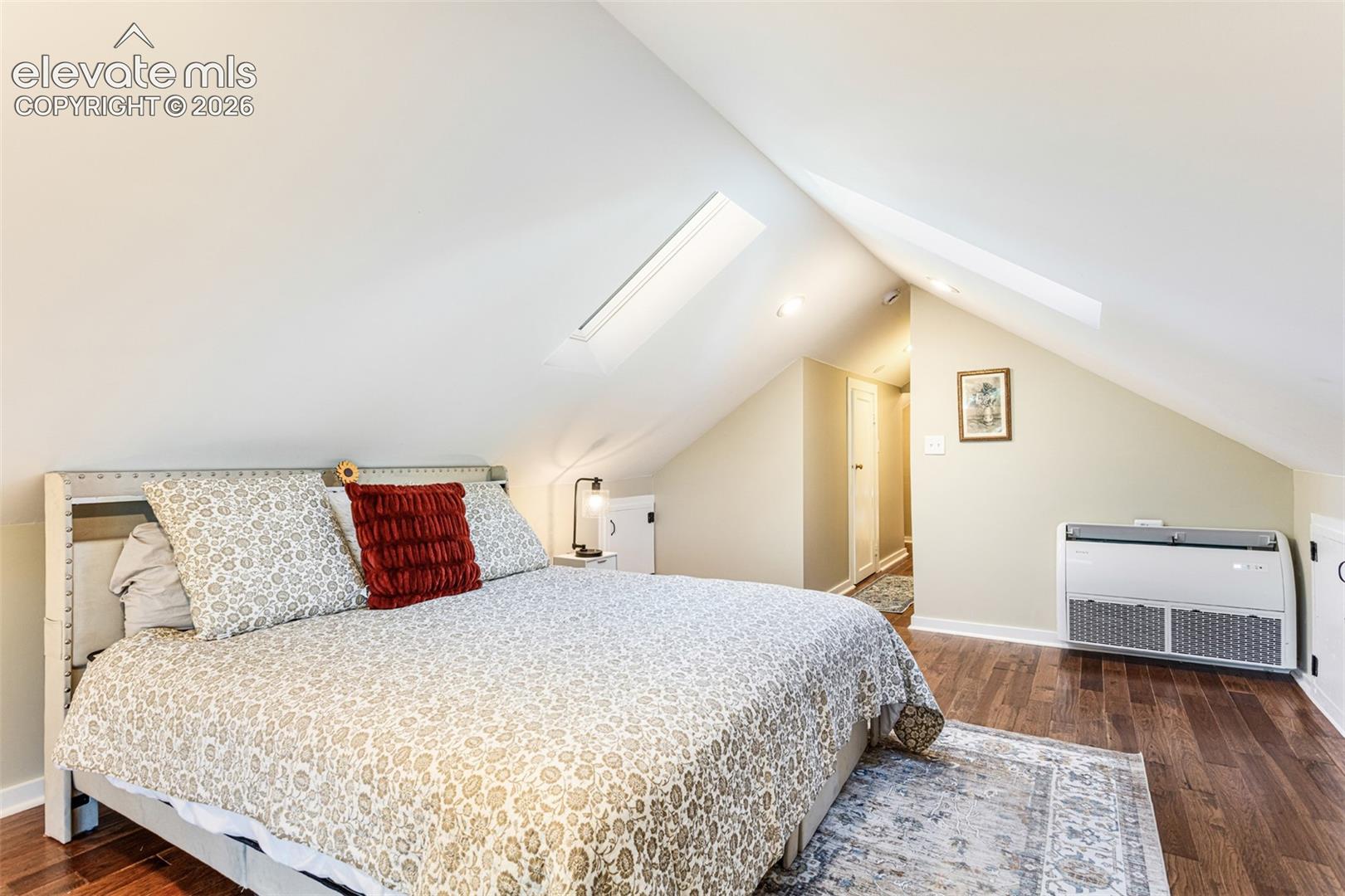 Room with sloped ceilings featuring two skylights, recessed lighting, and wood-finish flooring