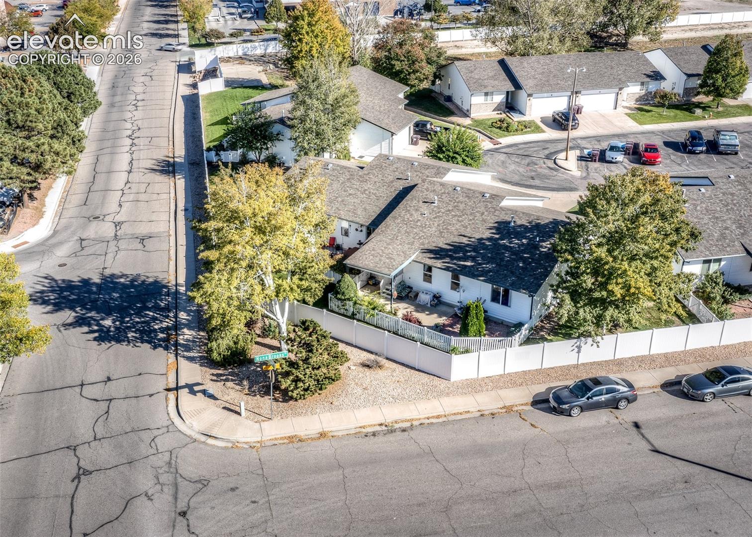 Corner lot property featuring a light-colored exterior, asphalt shingle roofing, and an enclosed privacy fence