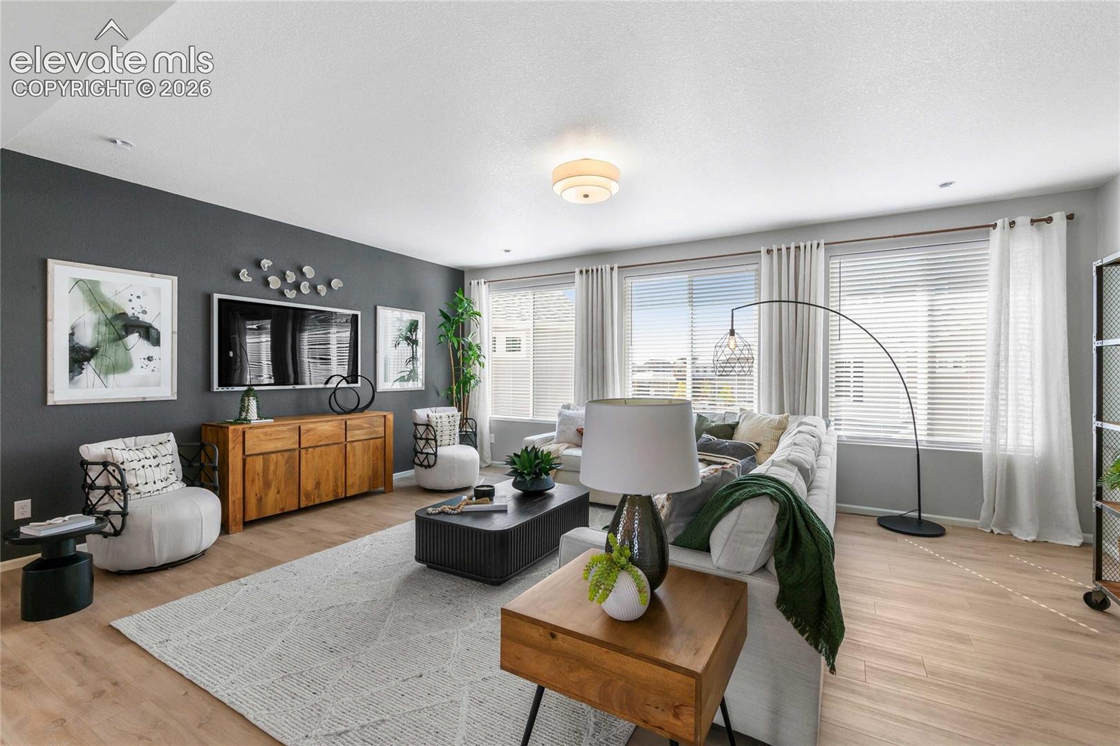 Expansive living area with wood-finish flooring, a wall of windows, and a built-in ceiling light fixture
*photos of a model home*