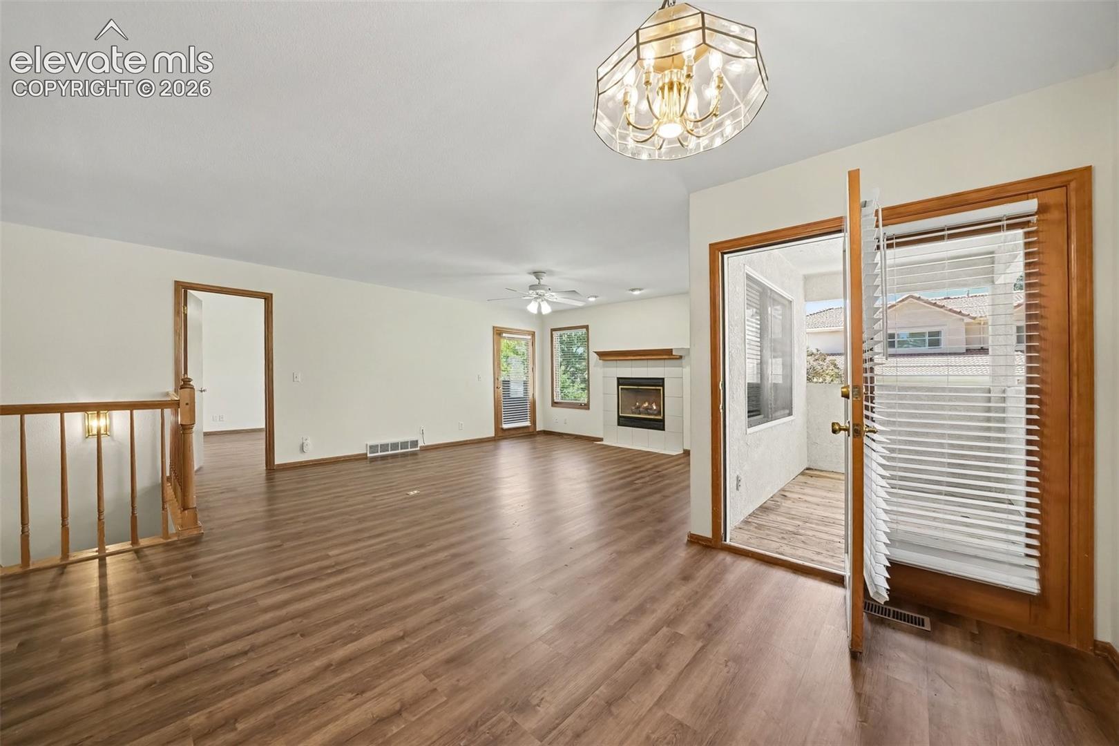 Spacious living area featuring new paint and new LVP flooring, a built-in gas fireplace with a white mantel, and a decorative chandelier