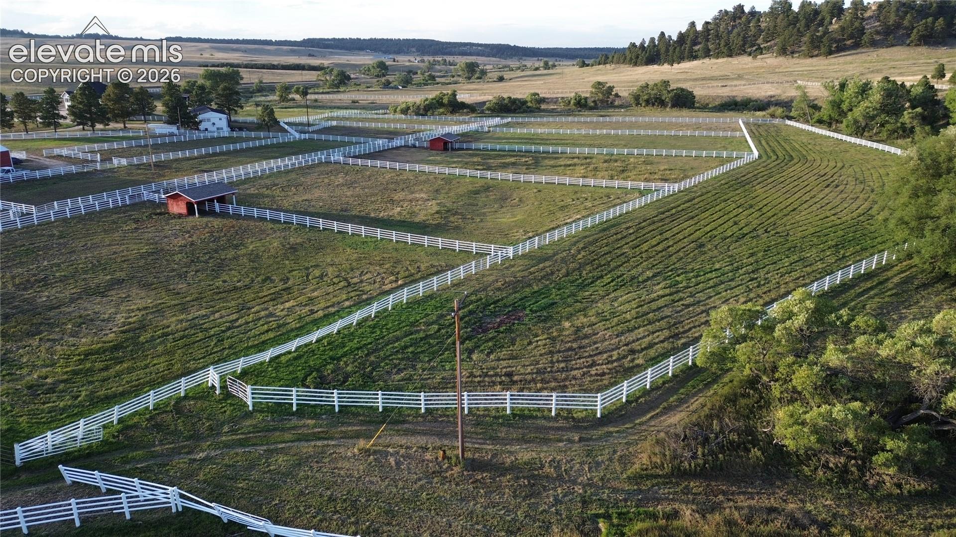 Expansive land parcel featuring multiple fenced enclosures, rolling terrain, and distant natural scenery