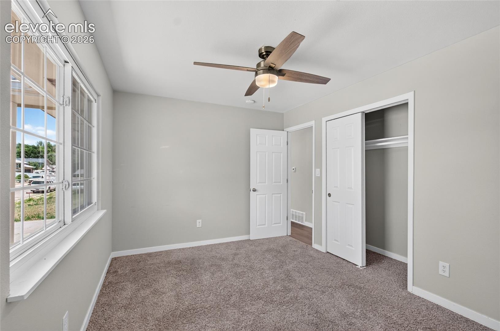 Bedroom featuring textured carpet flooring, light gray wall paint, and a multi-pane window